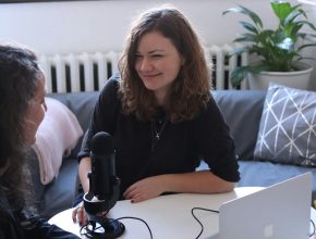 woman in black half sleeved shirt sitting while facing woman and smiling